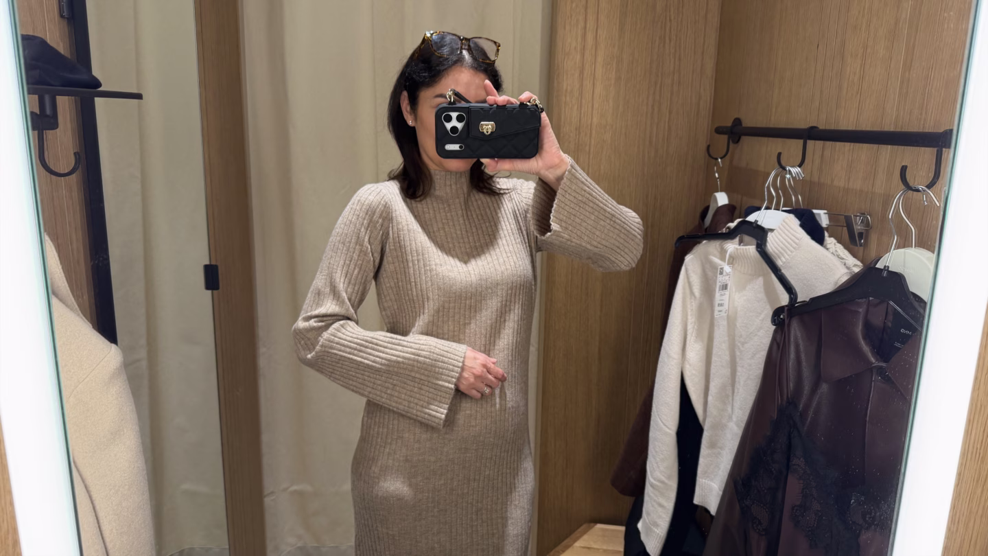 women trying on an ivory knit dress in afitting room