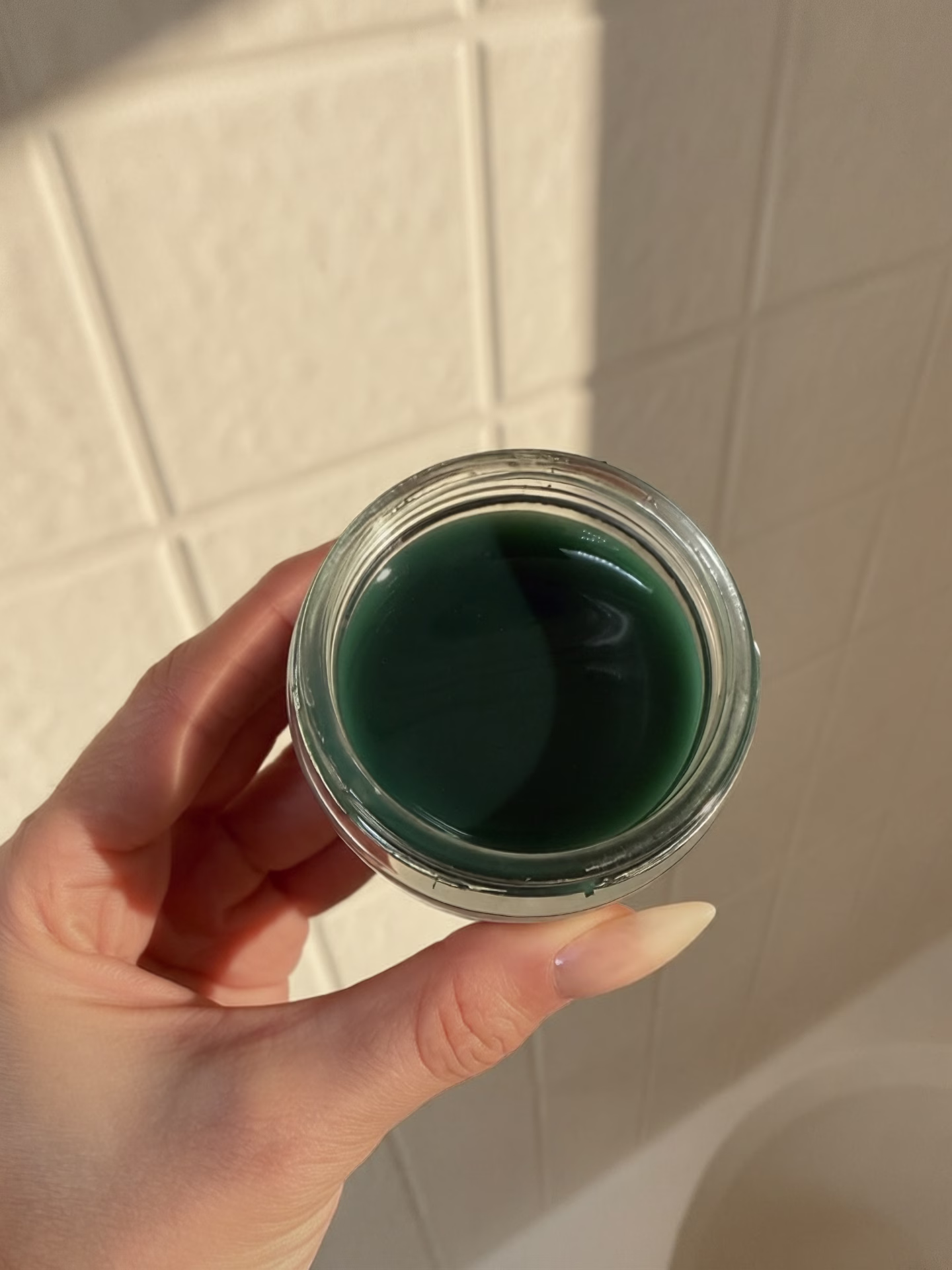 The image features a close-up of a clear glass skincare jar containing a turquoise gel product, likely a blue tansy resurfacing clarity mask, topped with a white lid. This gel mask is designed to gently exfoliate and promote glowing skin, making it suitable for sensitive skin types.